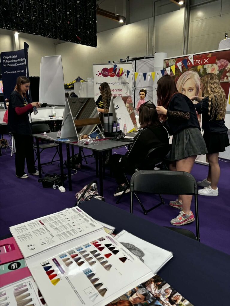 Stoisko na targach. Na stole ulotki i misa z cukierkami