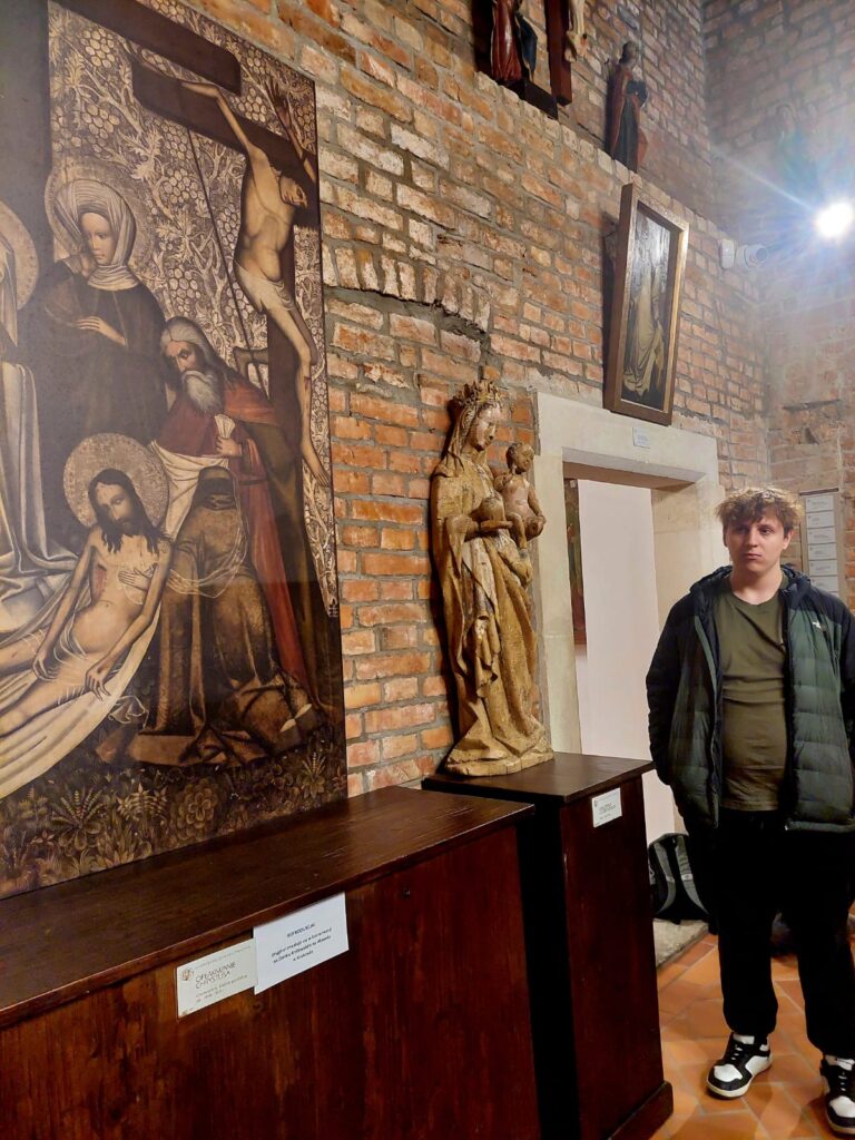 Uczeń stoi obok figury Matki Bożej